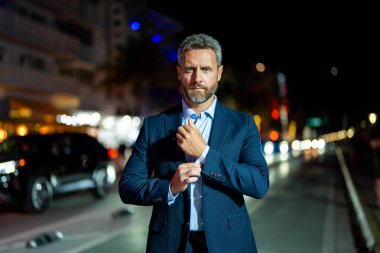 Gece vakti poz veren başarılı bir iş adamı. Gece sokağında takım elbiseli zengin bir işadamı duruyor. Resmi takım elbiseli yakışıklı bir iş adamı. Şık bir iş adamı. Zarif iş adamı.