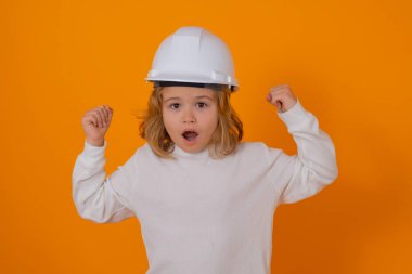 Kasklı, inşaatçı üniformalı bir çocuk. Kasketli genç mimarın stüdyo portresi. Heyecanlı Çocuk tamircisi. Çocuk inşaat işçisi. Çocuk müteahhit. Tamirci kıyafeti giymiş çocuk.