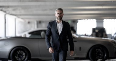 Olgun bir iş adamı. Lüks bir arabanın yanında duran zengin bir işadamı. Küresel. Endüstri lideri. Başarılı bir iş. Pahalı bir arabanın önünde duran şık, lüks bir iş adamı.