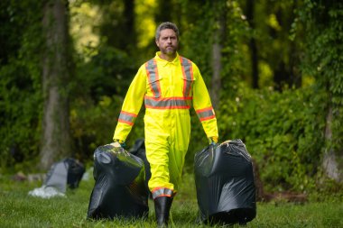 Gönüllü adam çöpleri topluyor, doğadaki atıkları topluyor. Toprak kirliliği, çevresel sorunlar. Plastik çöp yığını doldur. Doğanın kirliliği. Ekoloji konsepti. Çevre kirliliği