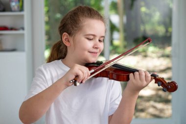 Çocuk evde keman çalıyor. Klasik müzik kemanı olan bir çocuk. Genç kemancı iç mekanda şarkı öğreniyor. Çocuk ders sırasında keman çalıyor. Evde keman eğitimi alan bir genç.