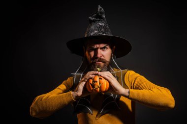 Cadılar Bayramı balkabaklı komik bir model. Cadılar Bayramı şapkalı balkabaklı insan portresi. Şeker mi şaka mı? Cadılar Bayramı şapkalı korkunç hippi. Cadı şapkalı adam balkabağını tutuyor. Mutlu Cadılar Bayramı