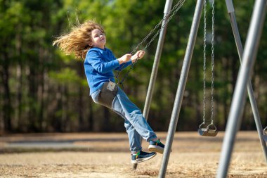Heyecanlı çocuk eğleniyor. Çocuk bahçesinde mutlu bir çocuk. Havada sallanan kaygısız çocuk. Mutlu çocuklar dışarıda oynuyor. Sarışın çocuk heyecandan titriyor. Dışarıdaki oyuncu çocuk. Komik çocuk suratı