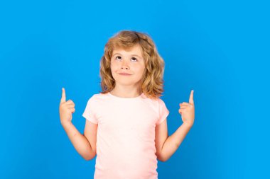 Child boy pointing up on isolated studio background. Kid with index finger pointing up on copyspace