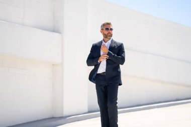 Dışarıda yürüyen bir iş adamı. Takım elbiseli başarılı bir iş adamı. Takım elbiseli kendine güvenen bir iş adamı. İşadamı çekip gidiyor. Zarif takım elbiseli zengin adam. Kendine güveni olan bir iş adamı. Başarı işi