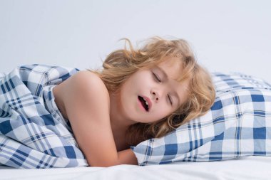 Yawning child. Kid lying in bed, waking up. Morning awakening, sunny kids bedroom