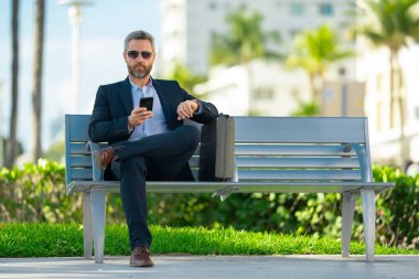 Kendine güveni tam bir iş adamı. Yaz parkında dizüstü bilgisayar ve telefonla bankta oturuyor. Başarı uzaktan yapılan bir iş. Orta yaşlı iş adamı tatilin tadını çıkarıyor. İş adamı bir bankta mola veriyor.