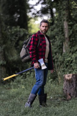 Ormanda baltası olan çalışkan bir adam. Büyük baltası olan sakallı bir oduncu. Ekose gömlekli vahşi sakallı bir adamın portresi bir balta tutuyor. Erkek güzelliği ve erkeklik