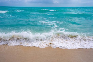 Deniz arka planı. Mavi okyanus. Kumlu okyanus plajı. Okyanus dalgaları. Yaz mevsimi. Tropik okyanus kıyısı. Egzotik turkuaz su. Köpüklü dalga denize sıçrıyor. Güneşli sahil manzarası