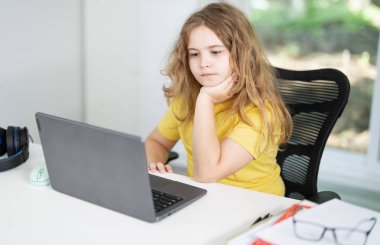 Genç okul çocuğu evde okulunu dinlerken notlar yazıyor. İnternetten ders alan çocuk. Evde eğitim gören bir çocuk online eğitim için dizüstü bilgisayar kullanıyor. Çocuk evde interaktif ders çalışıyor.