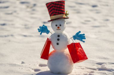 Kış arkaplanında bir Noel hediyesi kutusu tutan bir kardan adam. Karlı bir kış gününde hediyeli bir kardan adam. Kış sahnesinde kardan adamlar ve hediyeler. Noel hediyeleri. Kış ve Noel kutlaması