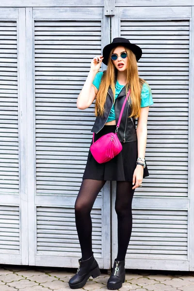 young beautiful woman with pink cross bag posing on street