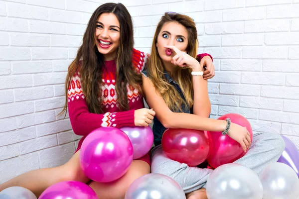 Funny positive portrait of hipsters best friends  having fun together, siting on the floor with pink balloons, happy party holidays.