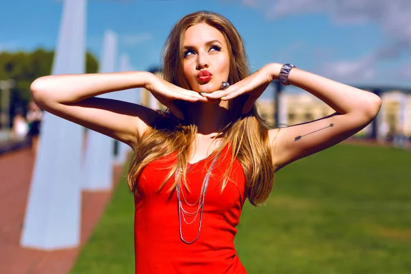 芝生でポーズ赤いドレスの若い美しい女性 — ストック写真