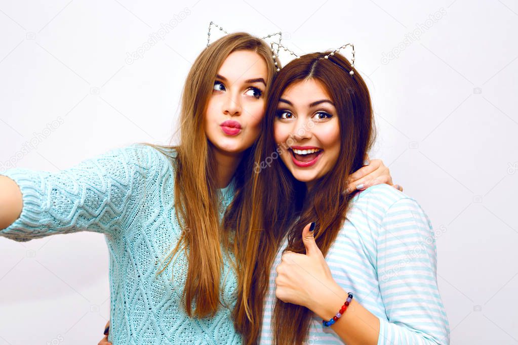 Close up fashion lifestyle portrait of two young hipster girls best friends taking selfie 