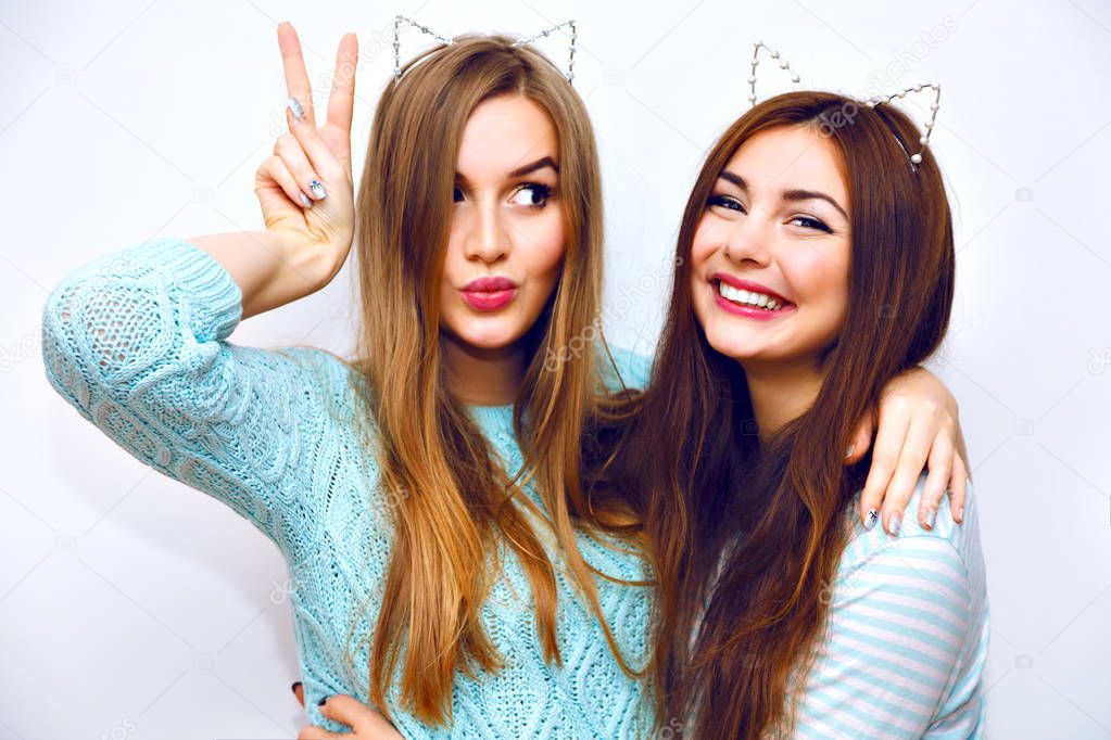Close up fashion lifestyle portrait of two young hipster girls best friends posing in studio