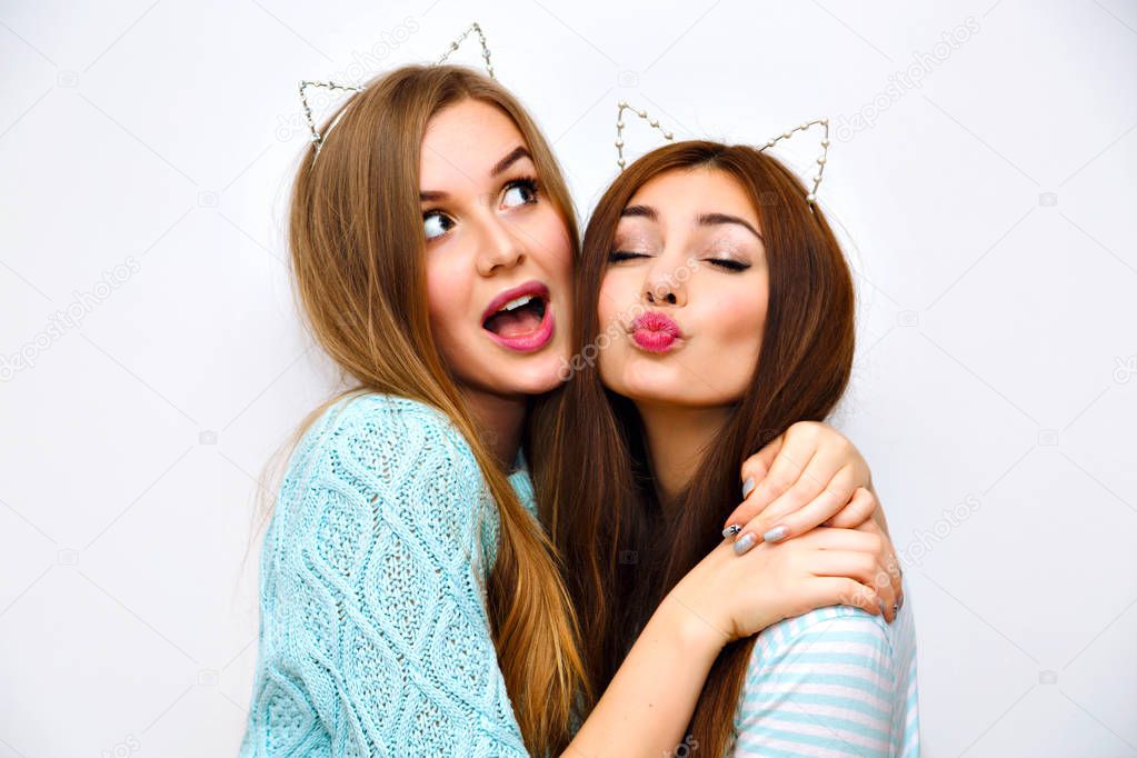Close up fashion lifestyle portrait of two young hipster girls best friends in ears hairbands posing in studio