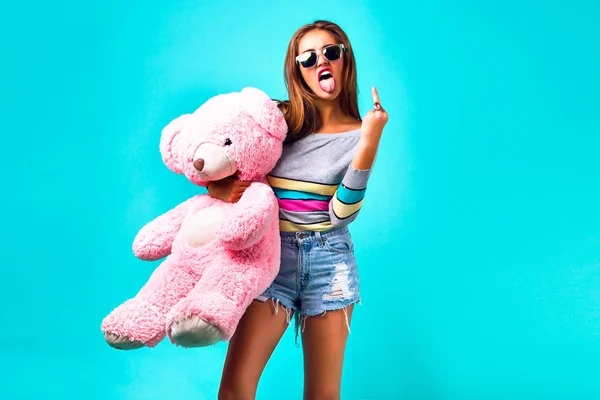 young beautiful woman with teddy bear showing middle finger