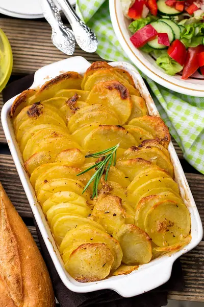 Baked crispy potato slices with rosemary served with vegetable salad