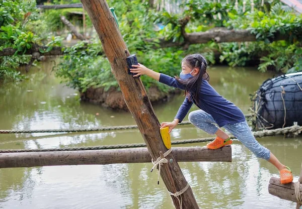 귀여운 아시아 소녀가 구조물을 통과하여 운하를 통과하려고 하면서 목적지에 도착하기 로열티 프리 스톡 사진
