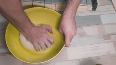 Plastik kasede hamur yoğuran bir adam. Karantina nedeniyle ev yapımı ekmek kavramı.