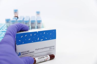 Dubai-UAE-Circa 2020: Doktor, covid-19 testi pozitif çıktı. Arka planda kan testleri tüpleri bulunan hidroklorokin ilaç kavramı. Coronavirüs, COVID-19 tedavisi.