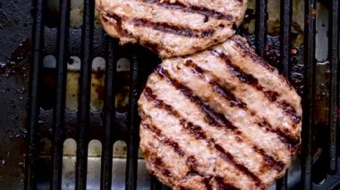 Elektrikli ızgarada ızgara yapan iki büyük biyo köfteli burger. Sağlıksız, yağlı, erkeksi yemek kavramı.