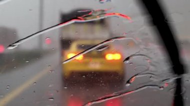 BAE, Dubai - 2020 dolaylarında: Araba ön cam manzarasına yağmur yağıyor. Trafik sıkışıklığında trafik sıkışıklığında araba sür. Şiddetli yağmur fırtınasında, bir arabanın içinde sür. Trafik lambası arkaplanı bulanık..