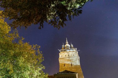 SIGHISOARA, ROMANIA - 2020 dolaylarında yıldızlı gökyüzü ile eski bir ortaçağ gece manzarası. Doğu Avrupa 'da güzel bir turistik yer. Sighisoara Romanya 'daki ünlü eski ortaçağ kulesi. Sakin gece konsepti