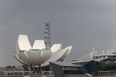 Singapur - CIRCA 2020: Arkaplanda fırtınalı bir gökyüzü bulunan Sanat Müzesi ve Singapur Flyer 'ın gündüz görüntüsü.
