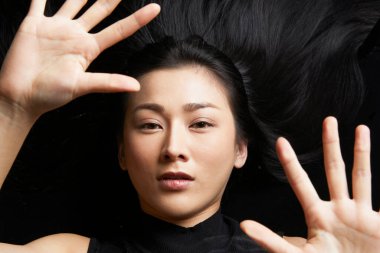 Asyalı kadınların cam altında parlak siyah saçları vardır. Güzellik konsepti. Saç bakımı, güzellik salonu, ameliyat, saç şampuanı, reklamcılık.