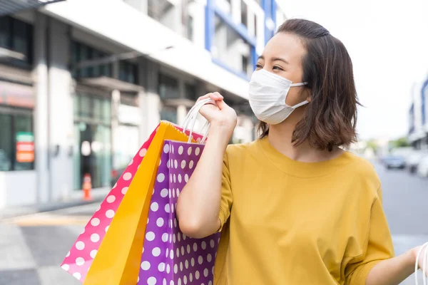 Asian women live a new normal life during the outbreak of COVID-19 . Asian women wear masks or face shield and holding shopping bags happily. Live a normal life during the epidemic.