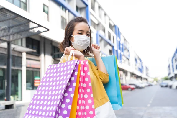 Asian women live a new normal life during the outbreak of COVID-19 . Asian women wear masks or face shield and holding shopping bags happily. Live a normal life during the epidemic.