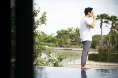 Asyalı adamlar havuz kenarında kahve içiyor.