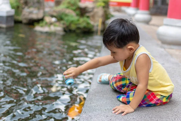 Lindos niños asiáticos están alimentando peces . — Foto de Stock