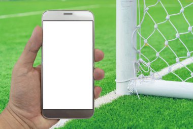 El Smartphone futbol alan arka plan ile tutarak.