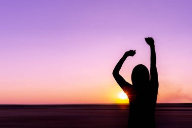 Deniz arka plan üzerinde gün batımında genç kadın silüeti.