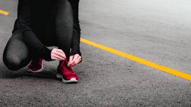 Genç kadın runner yol arka plan üzerinde ayakkabı bağlama.