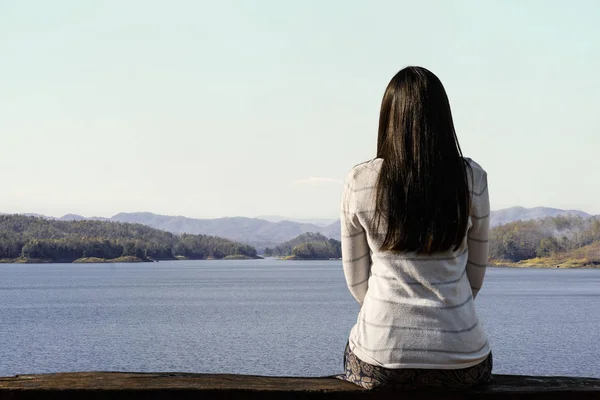 Jovem viajante mulher estão sentados olhando para o lago e céu sagacidade — Fotografia de Stock