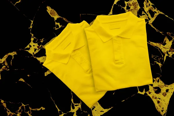 Yellow t-shirt on black marble table background