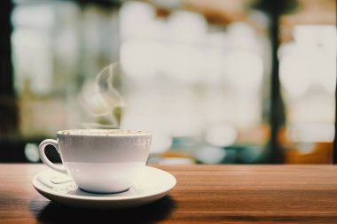 Arka plan için kafede ahşap masada sıcak kahve fincanı.
