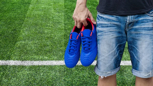 Elinde mavi futbol botları tutan adam. — Stok fotoğraf