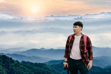 Genç fotoğrafçı, dağlarda sisli kış gündoğumunu gösteren bir kamera tutuyor.