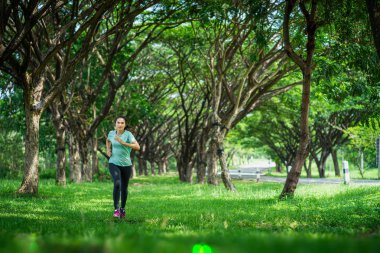 Genç Asyalı kadın doğada yolda koşuyor..