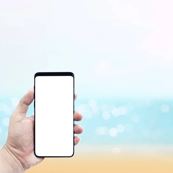 Рука держит смартфон с размытым морем в Саммере . — стоковое фото