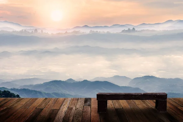 Old wood chair with beautiful foggy winter sunrise in mountains