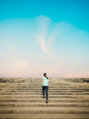 Sabah ları gökyüzü manzarasıyla merdivenlerde koşan kadın.