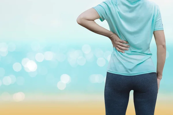 A young woman is run on the beach in the morning and having back pain.