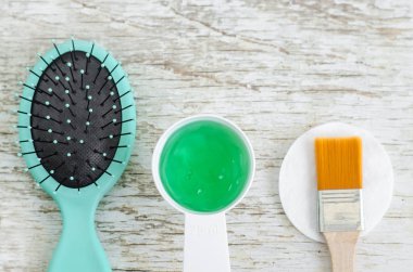 Saç fırçası ve yeşil jöle saç maskesi (kremi) spirulina, aloe vera ve deniz kollajen ile küçük kepçe ayıklar. Spa ve doğal cilt ve saç bakım kavramı. Üstten görünüm, kopya alanı. 
