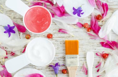 Çiçek ve meyve özleri ile beyaz yüz jel krem ve pembe maske ile iki küçük top. Spa ve doğal cilt bakım kavramı. Üstten görünüm, kopya alanı. 
